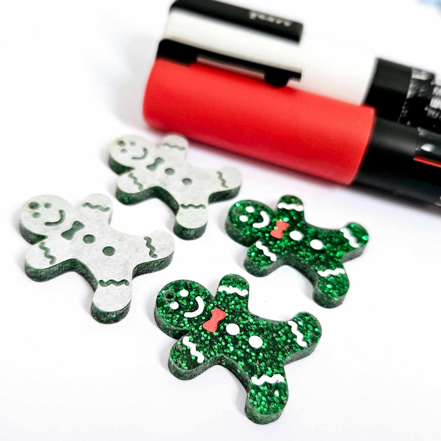 green glitter acrylic gingerbread men earring blanks that have been paint filled with red and white posca paint pens