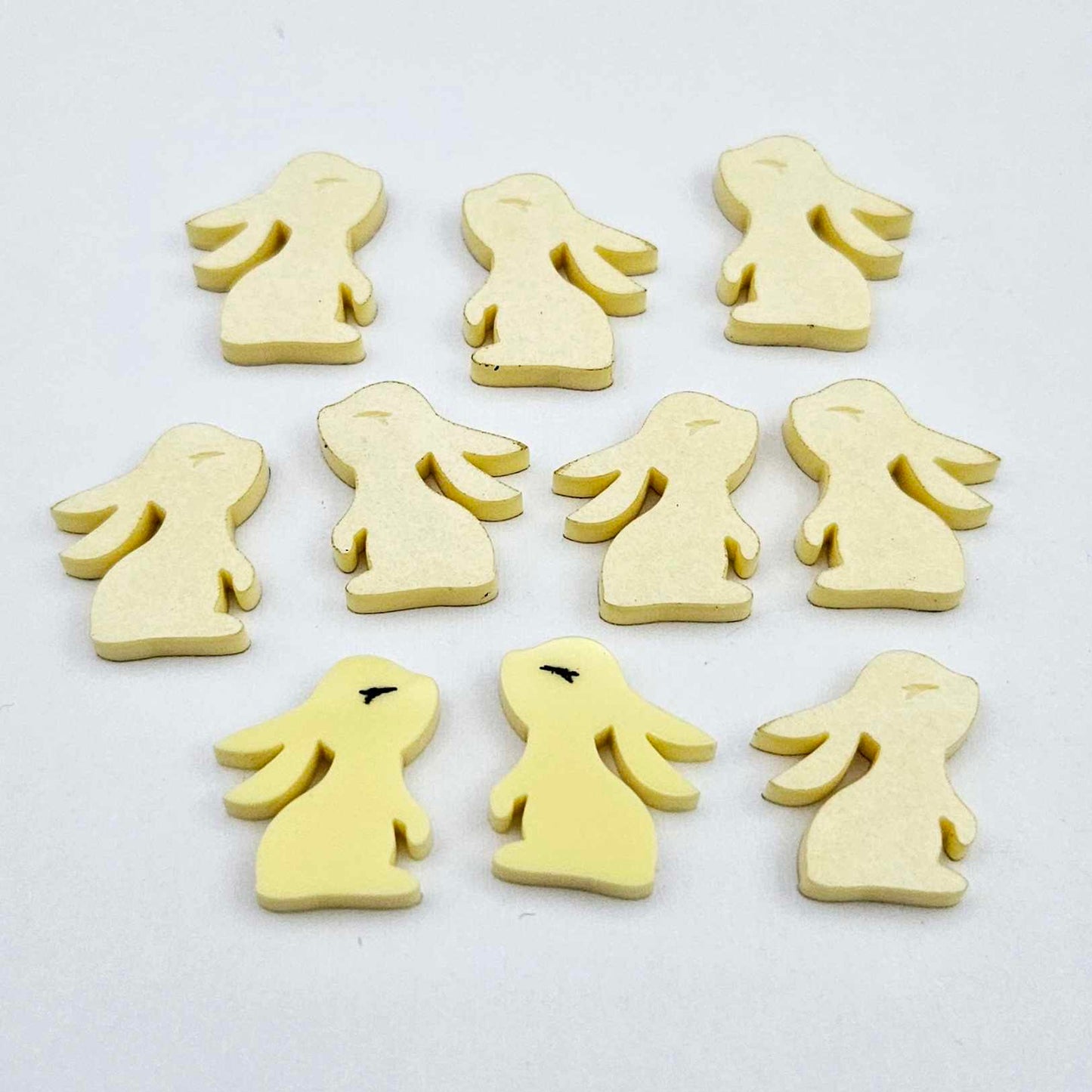Pastel yellow bunny stud blanks showing finished paint filled black eyelashes on two studs, with the rest shown as supplied with protective film