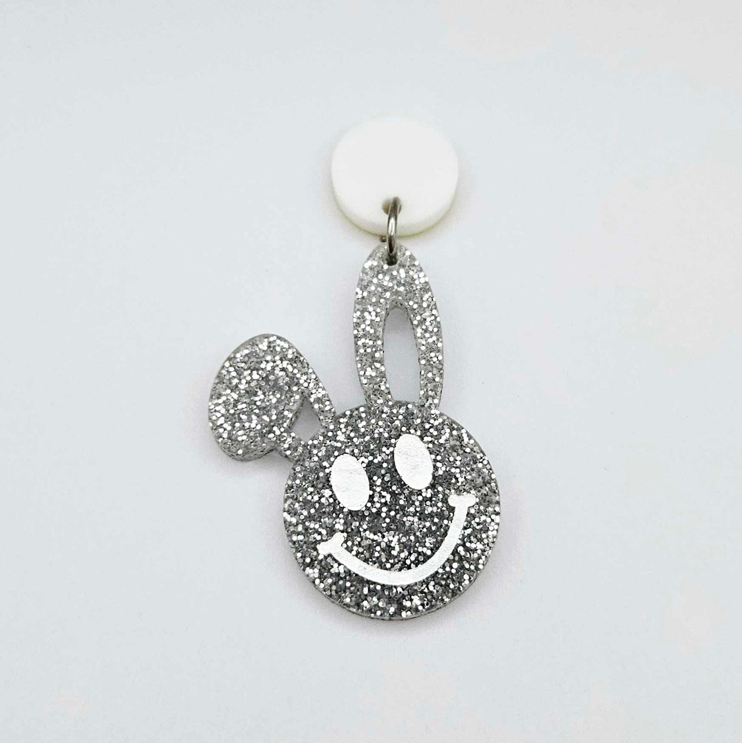 38mm silver glitter acrylic bunny dangle earring blank hanging from a 14mm white acrylic topper, bunny head with floppy ear and paint filled smiley face