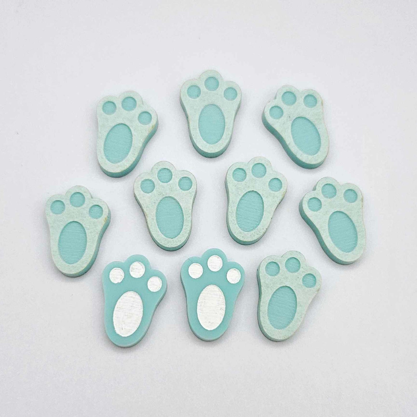 Pastel aqua bunny paw print stud blanks showing two paint filled white and several unpainted pieces