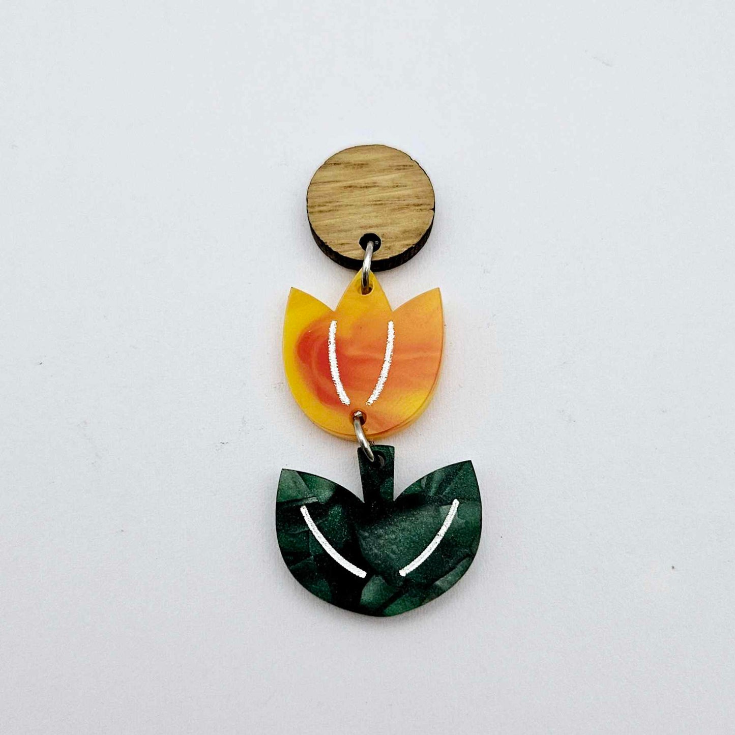 Assembled orange artist swirl and green mineral acrylic tulip dangle hanging from a 14mm oak wood topper, engraved detail paint filled white