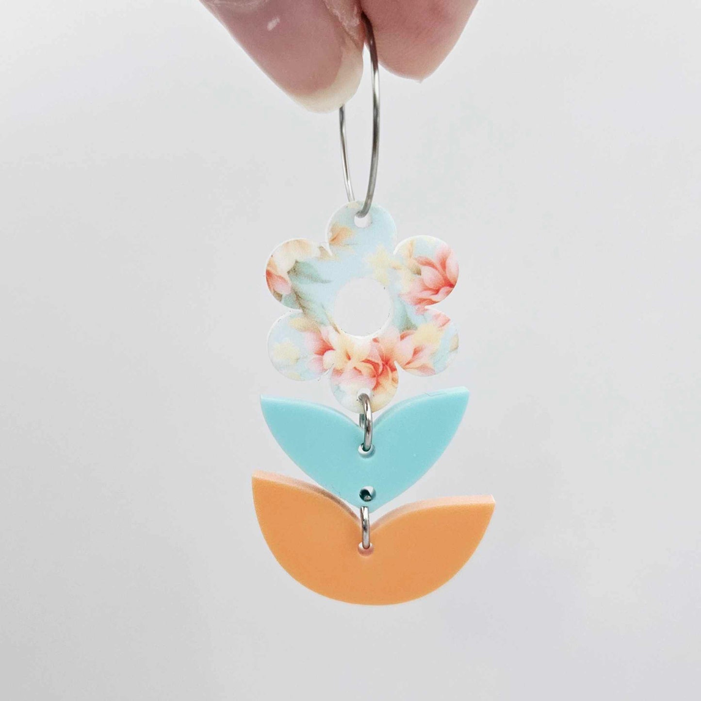Assembled three-piece acrylic flower dangle hanging from a 20mm hoop, UV printed Floral Bloom flower with aqua and orange leaf layers