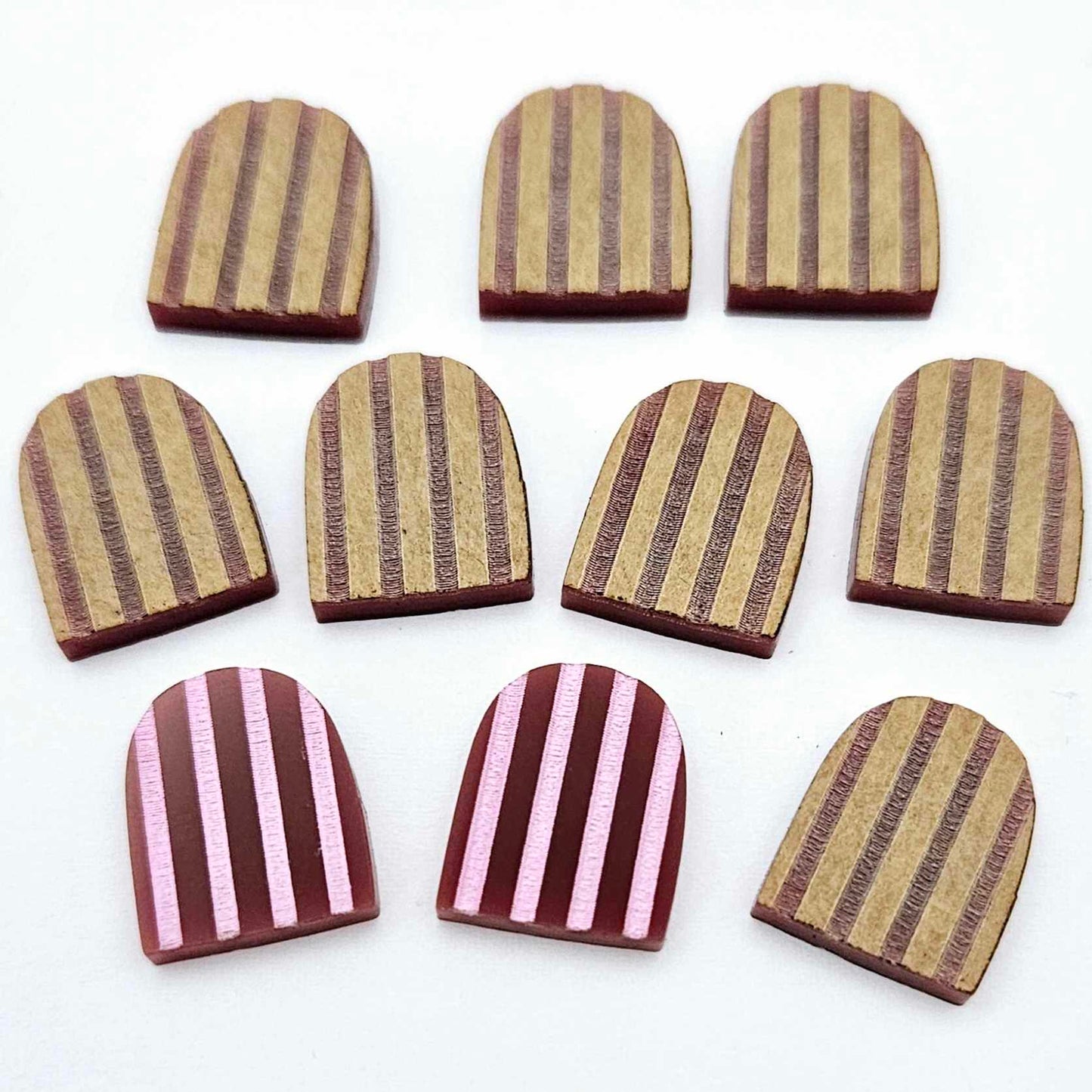 Port wine striped arch stud blanks with engraved stripes, one pair paint filled light pink and peeled, with additional unpainted pieces shown with protective film on
