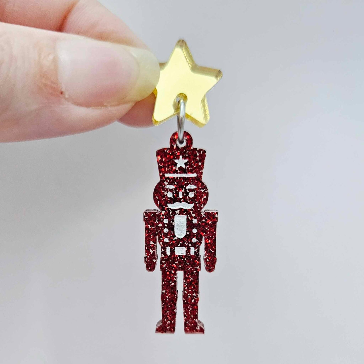 Assembled 40mm nutcracker Christmas dangle earrings in red glitter acrylic with engraved detail paint filled white