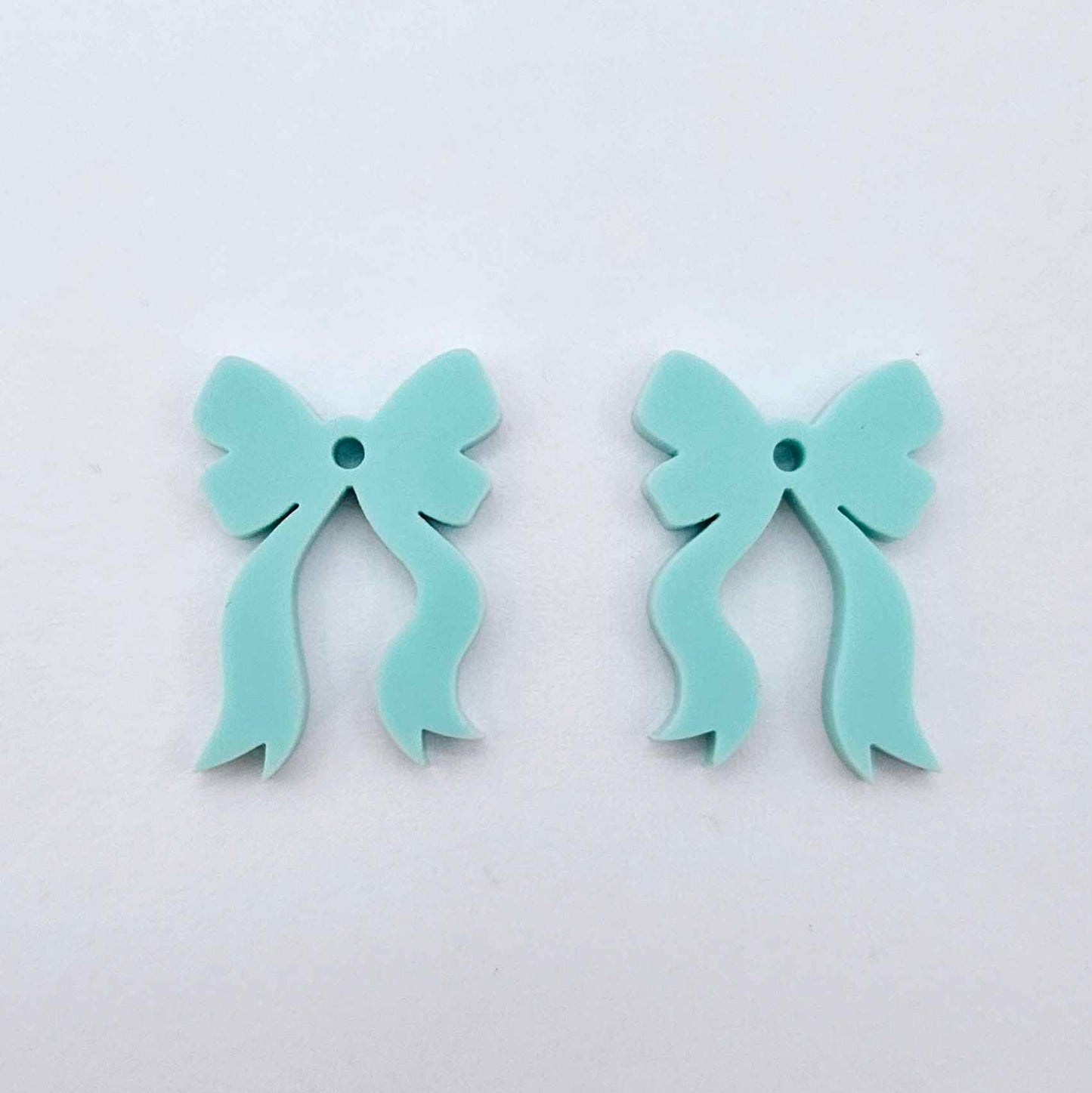 One pair of pastel aqua acrylic bow dangle earring blanks laying flat