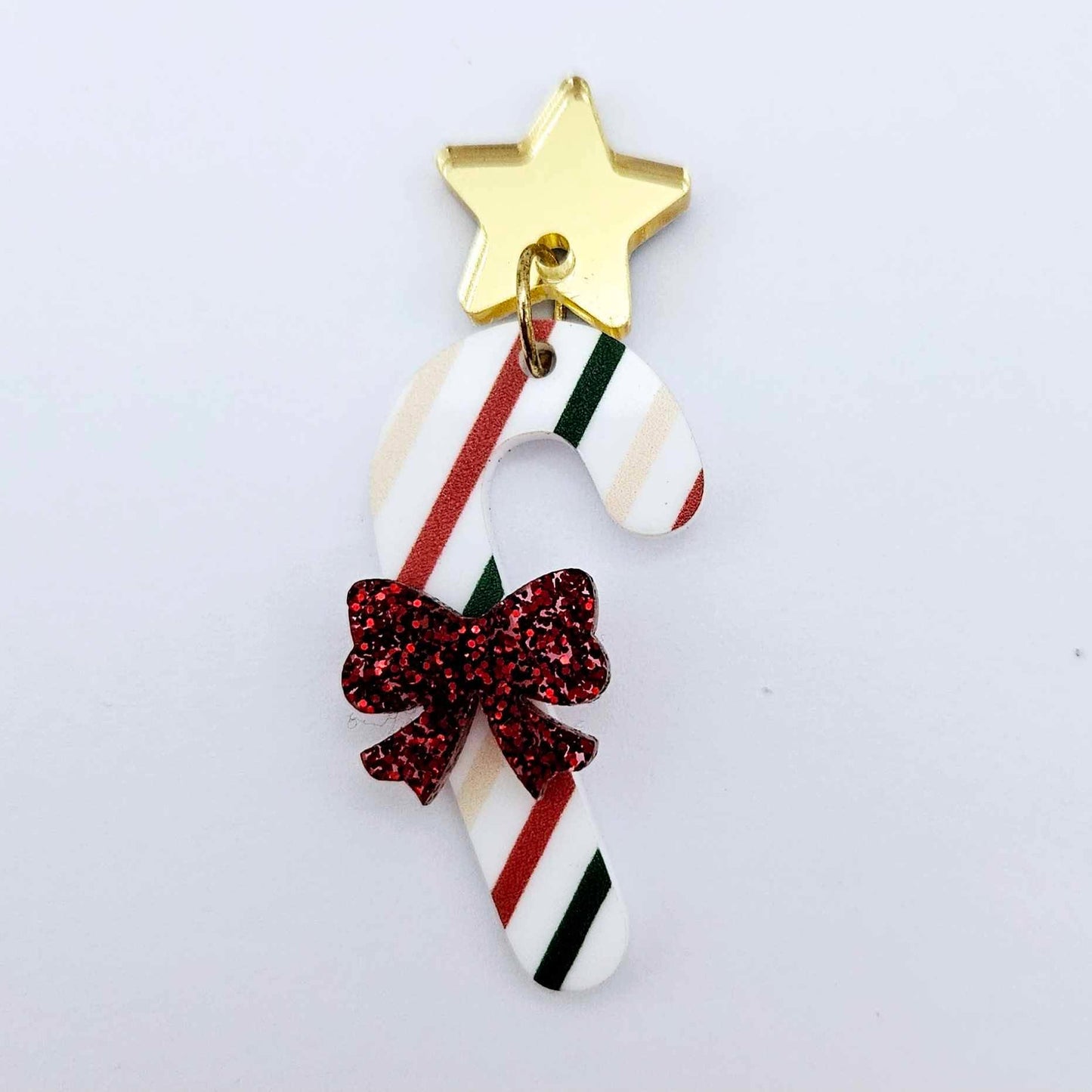 One Stripy Christmas UV printed acrylic candy cane dangle earring blank assembled with a red glitter bow and a 16mm gold mirror star topper, shown as a finished festive earring