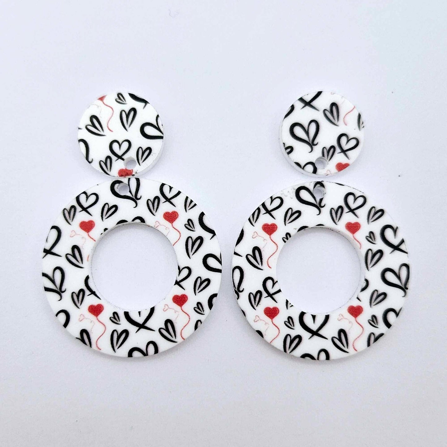 One pair of 33mm Black & Red Hearts UV printed acrylic mini hoop dangle earring blanks with matching toppers laying flat.