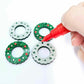 green glitter acrylic wreath earring blanks that are being paint filled with red and white posca paint pens