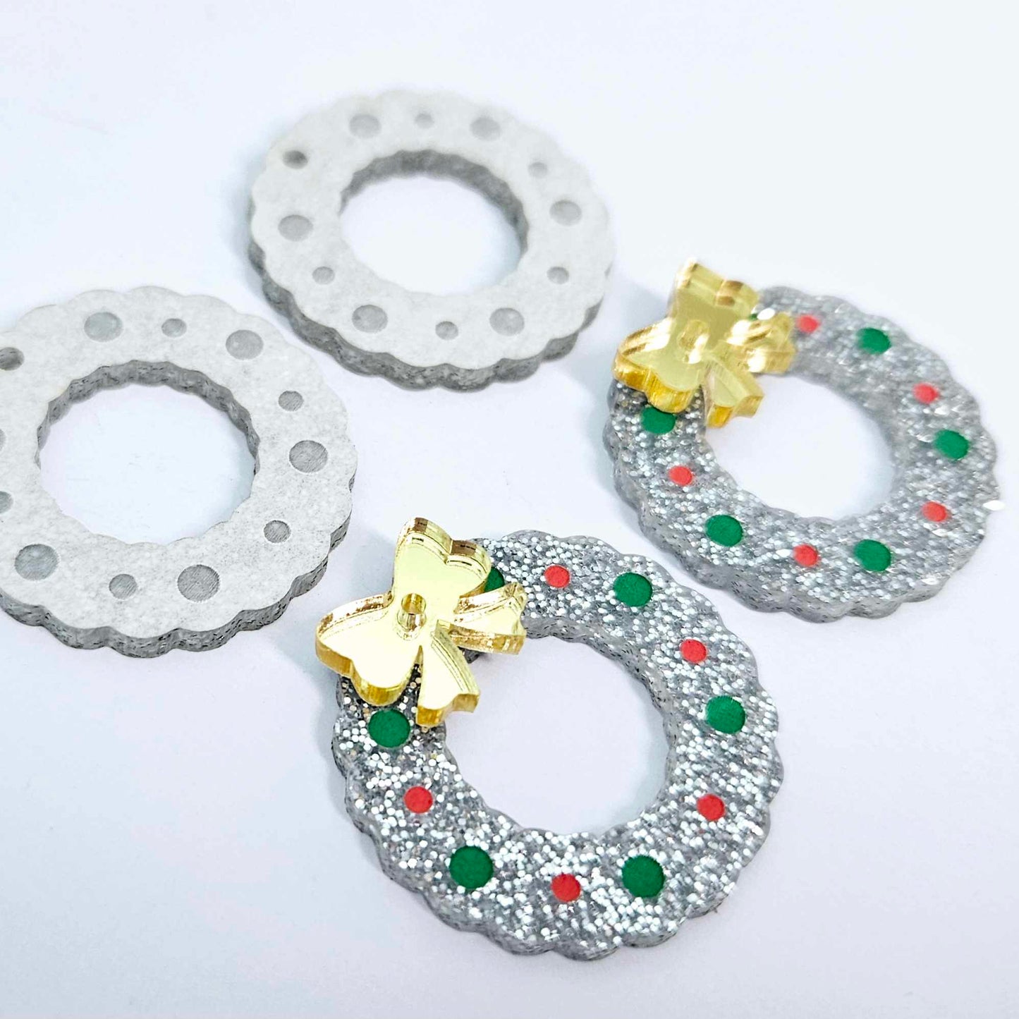 silver glitter acrylic wreath earring blanks that have been paint filled with green and red posca paint pens