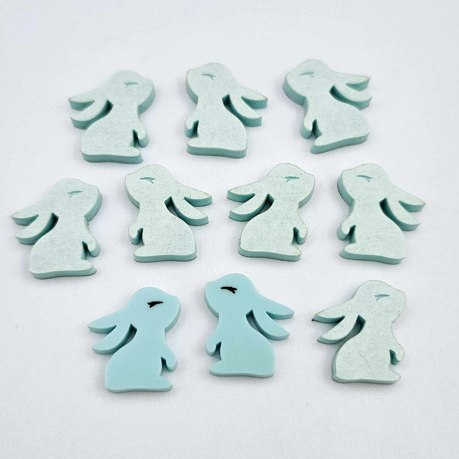 Pastel aqua bunny stud blanks showing finished paint filled black eyelashes on two studs, with the rest shown as supplied with protective film