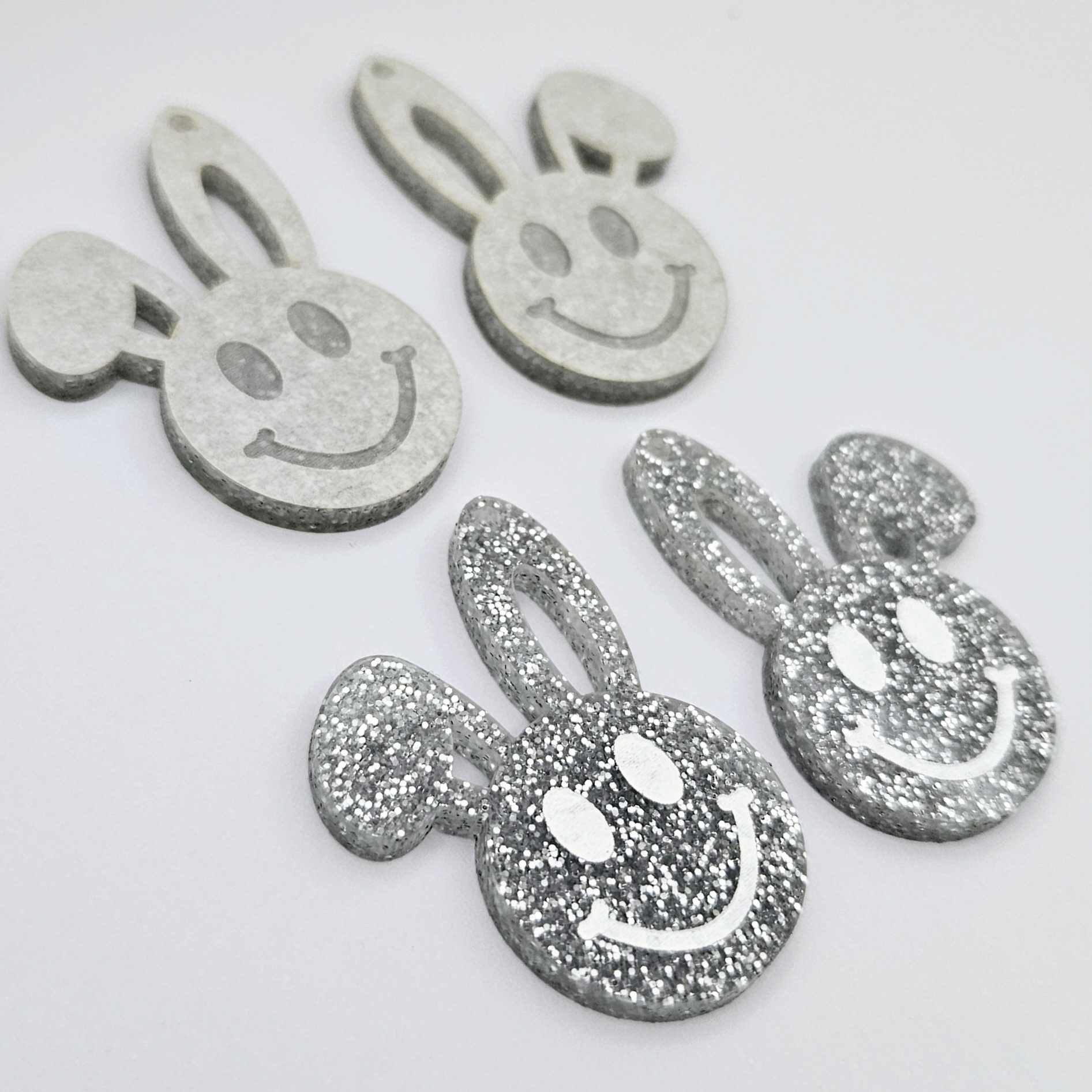 38mm silver glitter acrylic bunny dangle blanks with engraved smiley face, two paint filled white and two others unfilled with protective film on