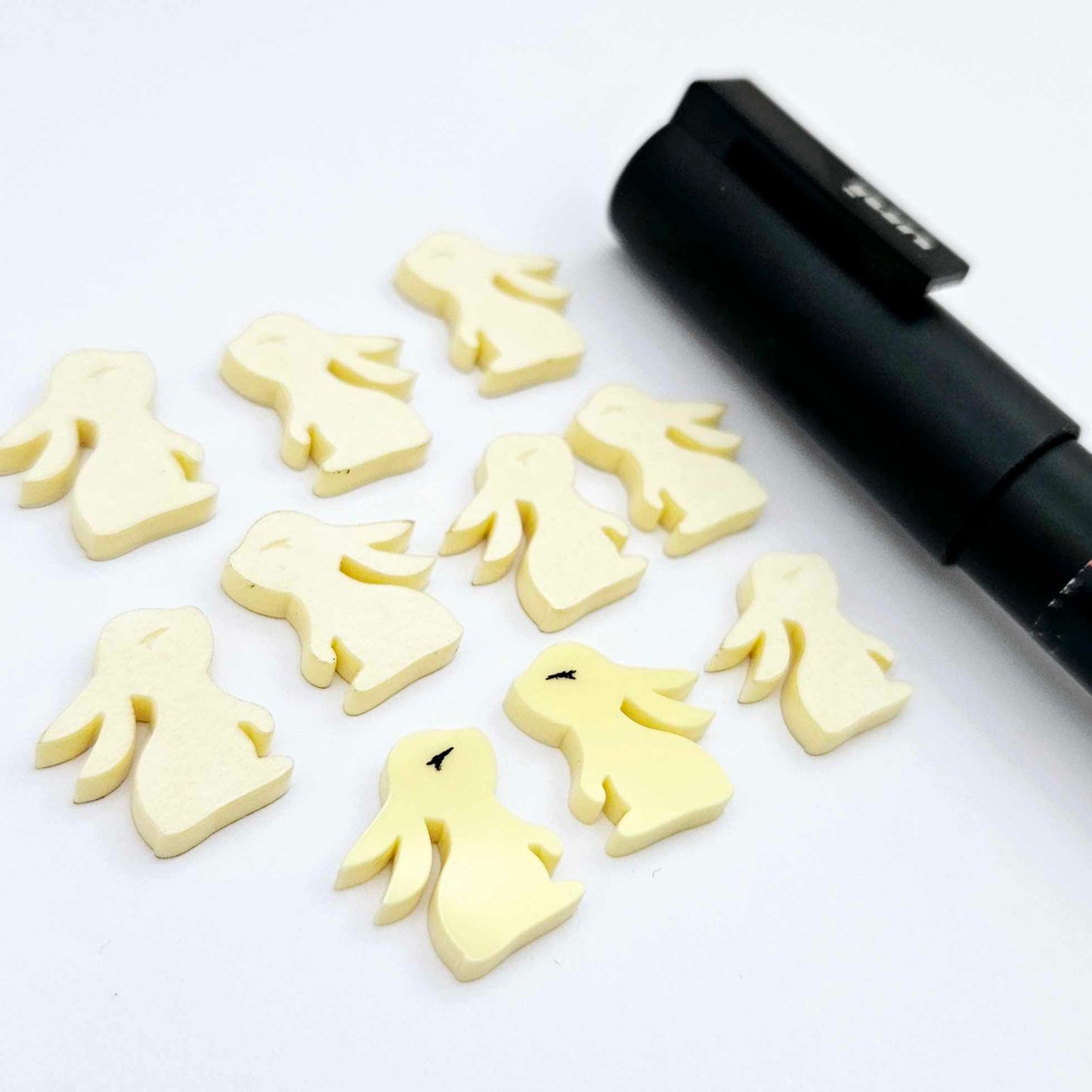 Pastel yellow bunny stud blanks showing finished paint filled black eyelashes on two studs, with the rest shown as supplied with protective film