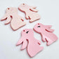 32mm Pastel pink bunny dangle blanks showing paint filled black eyelashes on two pieces, with remaining pieces shown with protective paper as supplied