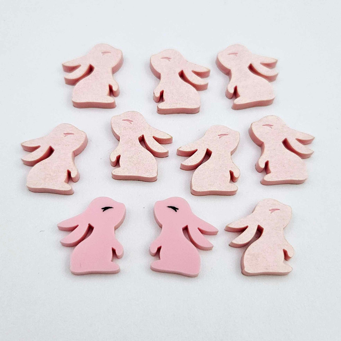 Pastel pink bunny stud blanks showing finished paint filled black eyelashes on two studs, with the rest shown as supplied with protective film