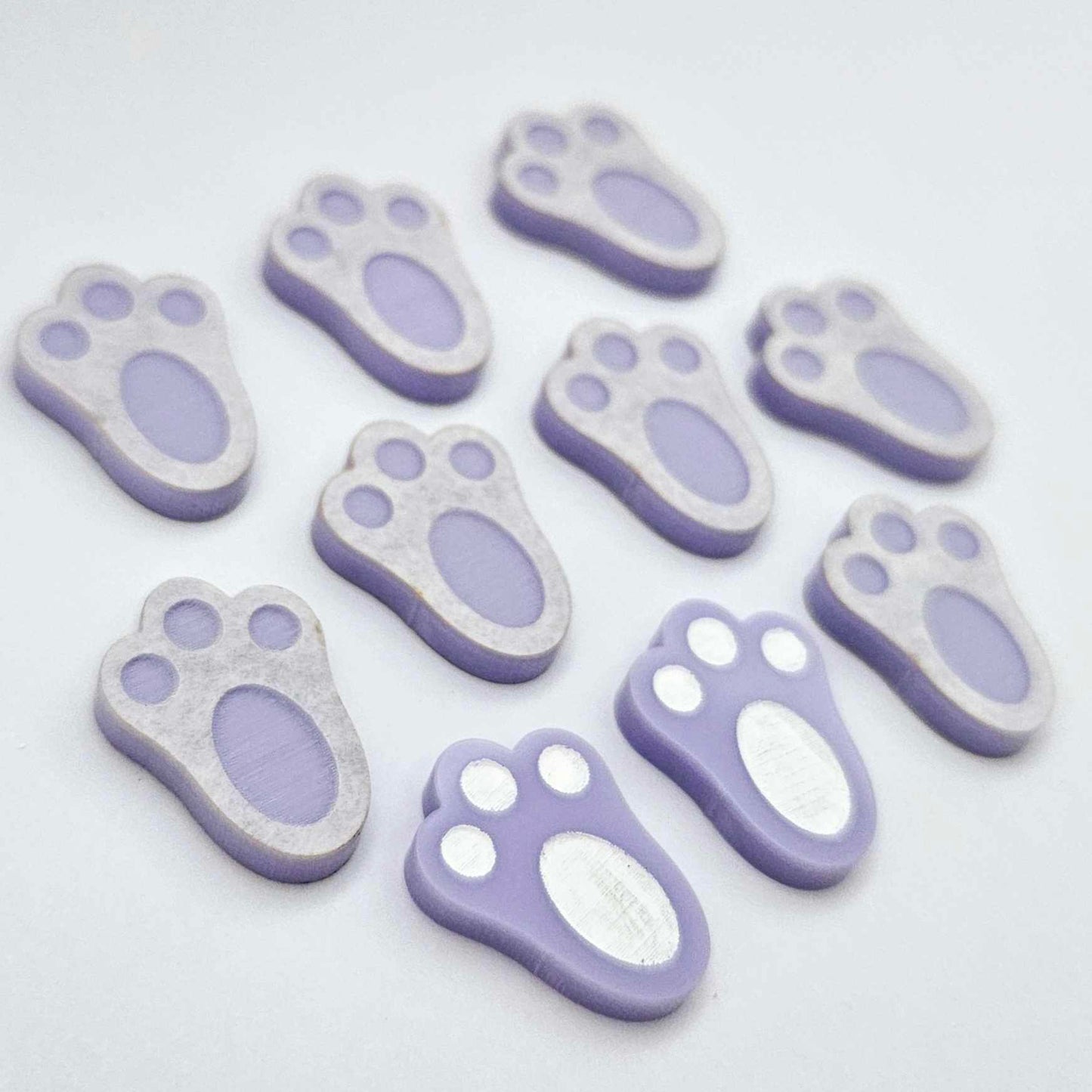 Pastel purple bunny paw print stud blanks showing two paint filled white and several unpainted pieces