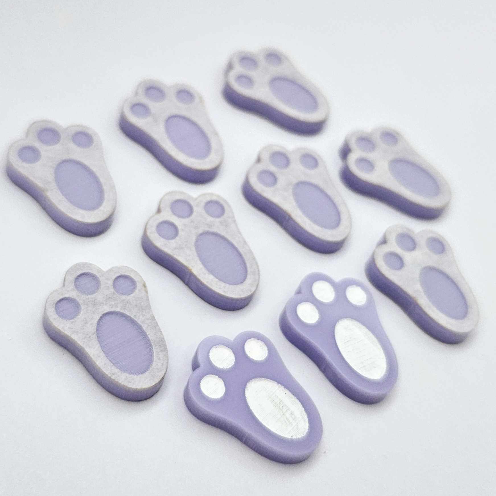 Pastel purple bunny paw print stud blanks showing two paint filled white and several unpainted pieces