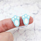 Close-up of two pastel aqua acrylic bunny paw print stud blanks with engraved pads paint filled white