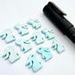 Pastel aqua bunny stud blanks showing finished paint filled black eyelashes on two studs, with the rest shown as supplied with protective film