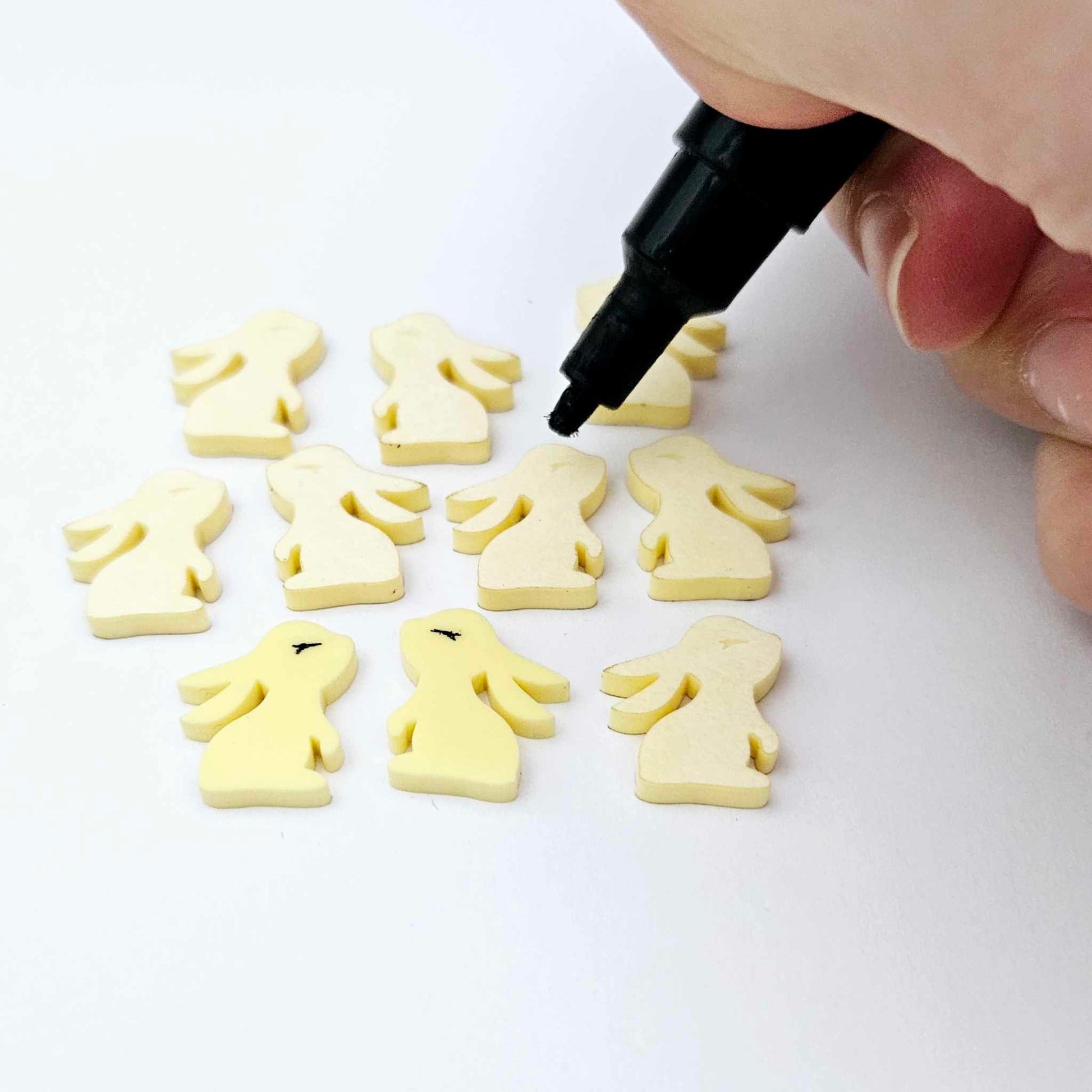 Pastel yellow bunny stud blanks showing finished paint filled black eyelashes on two studs, with the rest shown as supplied with protective film