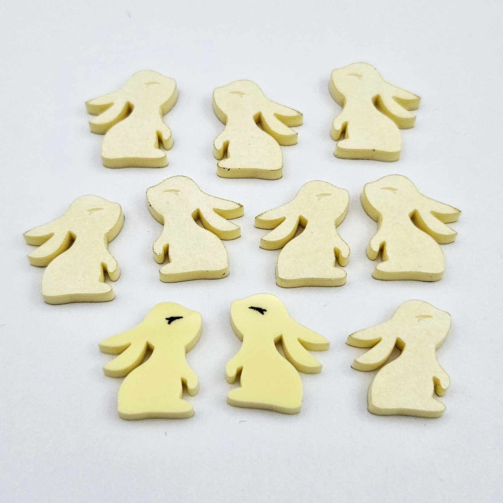 Pastel yellow bunny stud blanks showing finished paint filled black eyelashes on two studs, with the rest shown as supplied with protective film