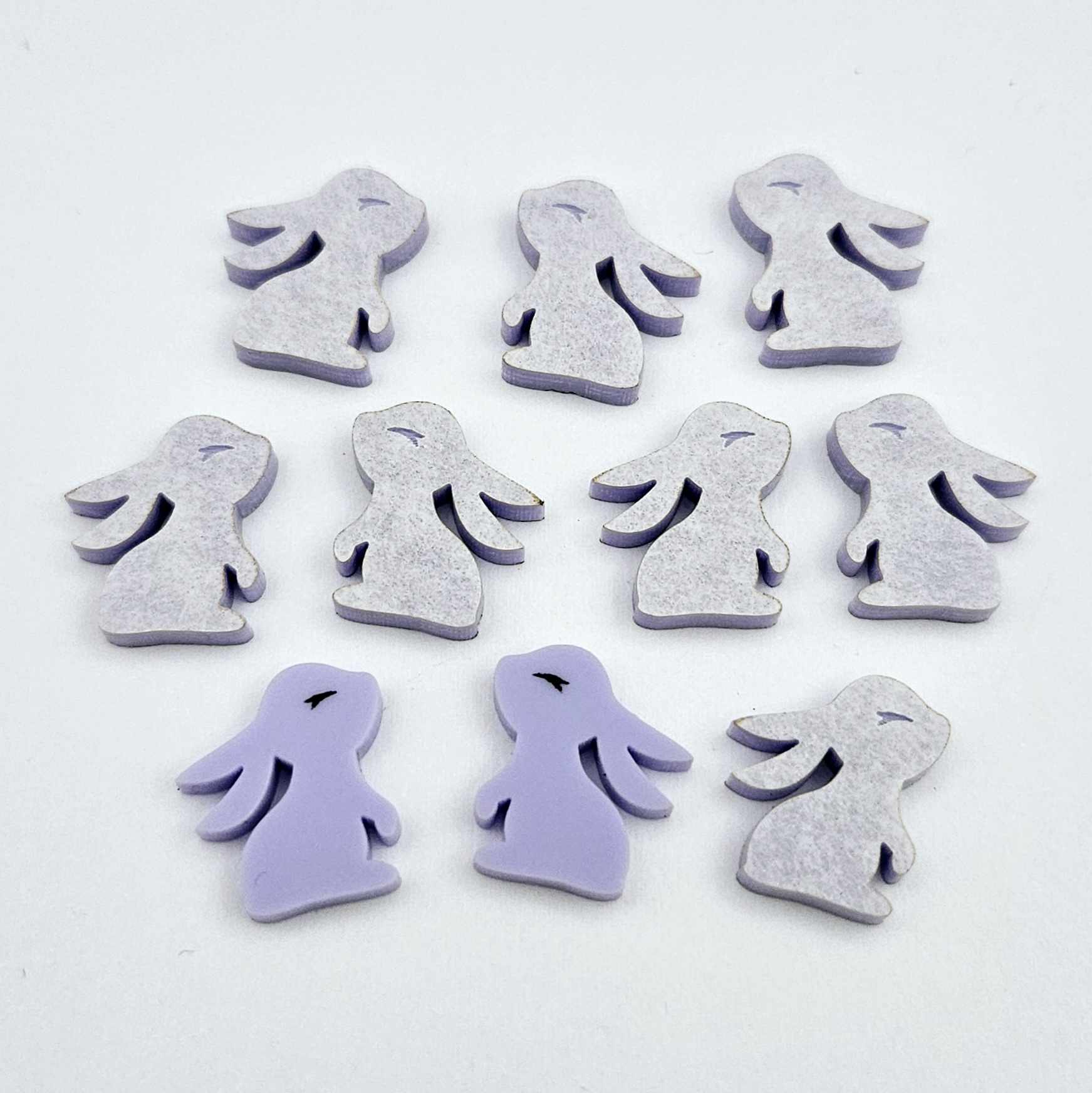 Pastel purple bunny stud blanks showing finished paint filled black eyelashes on two studs, with the rest shown as supplied with protective film