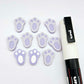 Pastel purple bunny paw print stud blanks showing two paint filled white and several unpainted pieces, with a white Posca paint pen included in the image