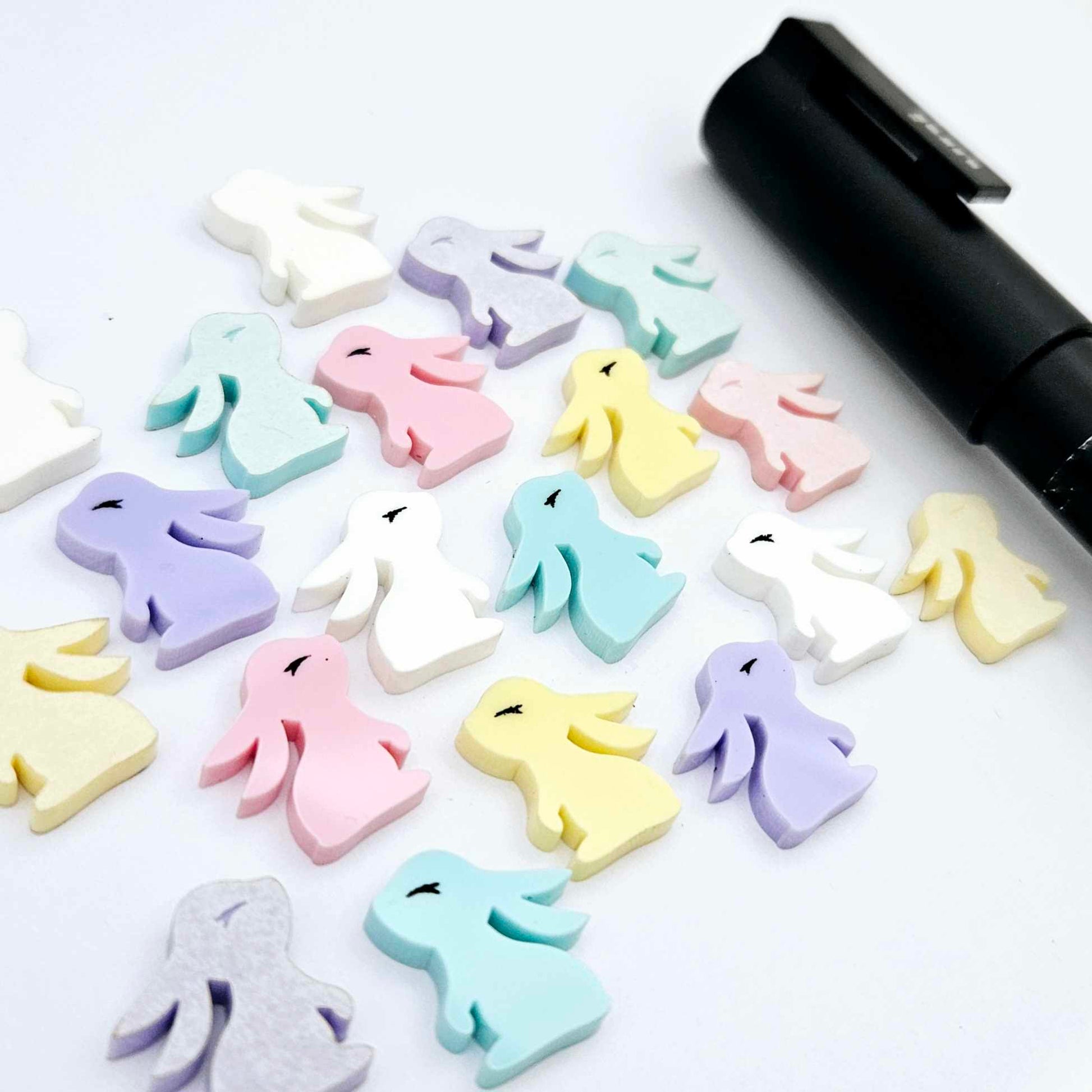 Pastel yellow, pink, purple, aqua and white bunny stud blanks (mixed pack) showing finished paint filled black eyelashes on two studs, with the rest shown as supplied with protective film