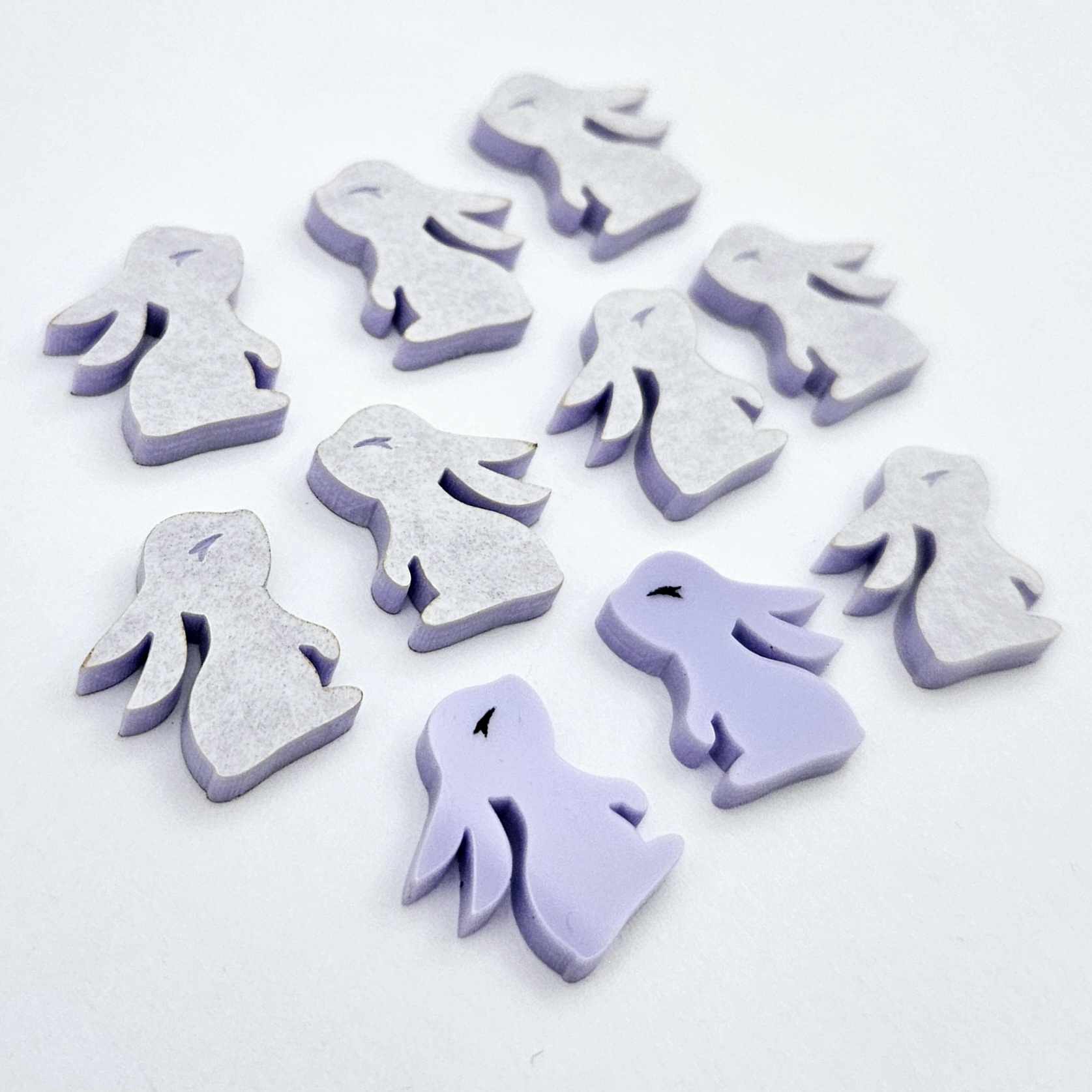 Pastel purple bunny stud blanks showing finished paint filled black eyelashes on two studs, with the rest shown as supplied with protective film