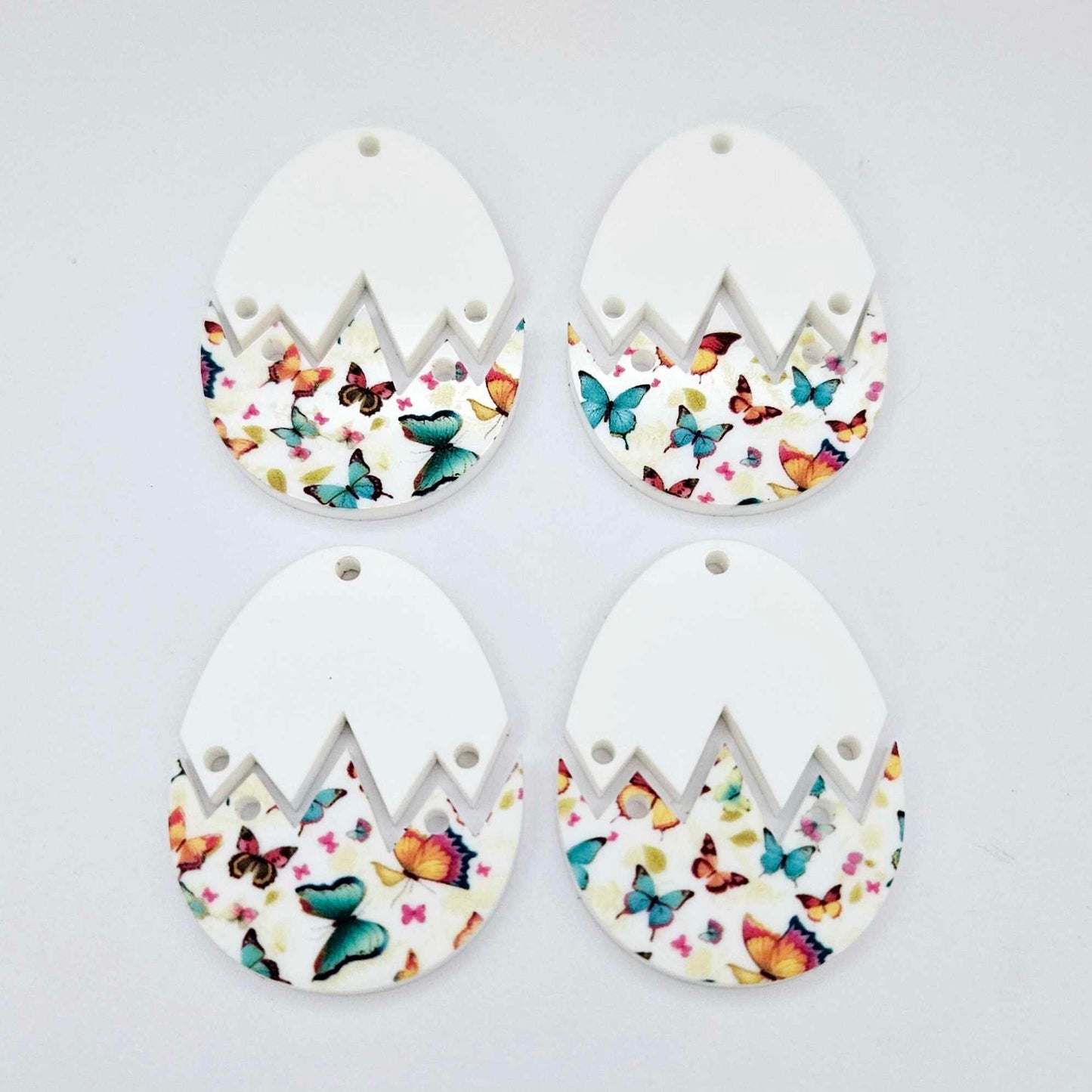 Four cracked egg acrylic Easter earring blanks unassembled, white top halves and butterfly UV printed bottom halves