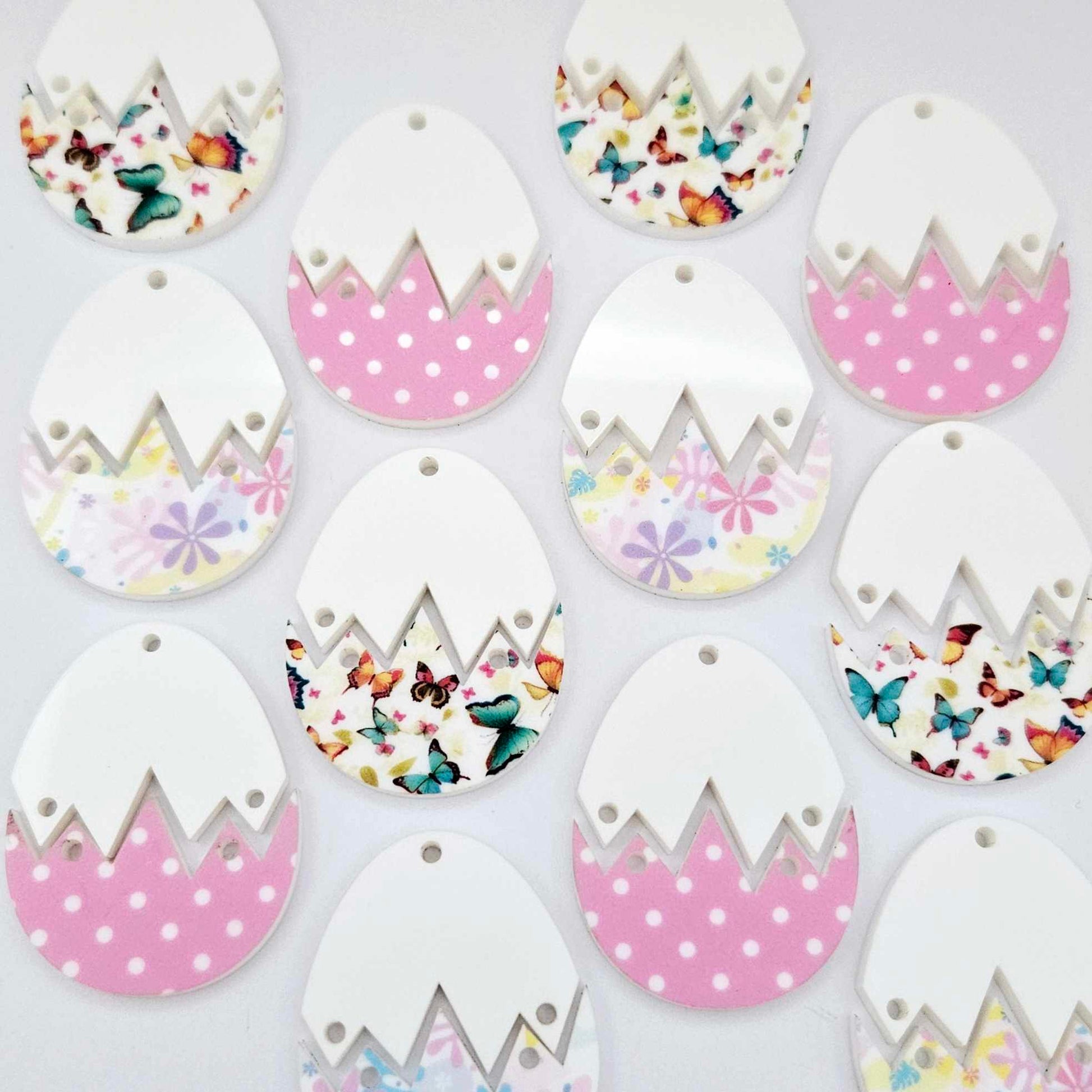 A mixture of cracked egg acrylic earring blanks unassembled, white top halves and different UV printed bottom halves