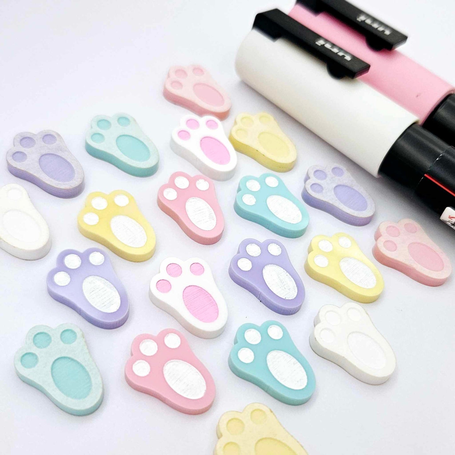 white and pastel bunny paw print stud blanks showing some paint filled and several unpainted pieces, with a Light Pink and White Posca paint pen included in the image
