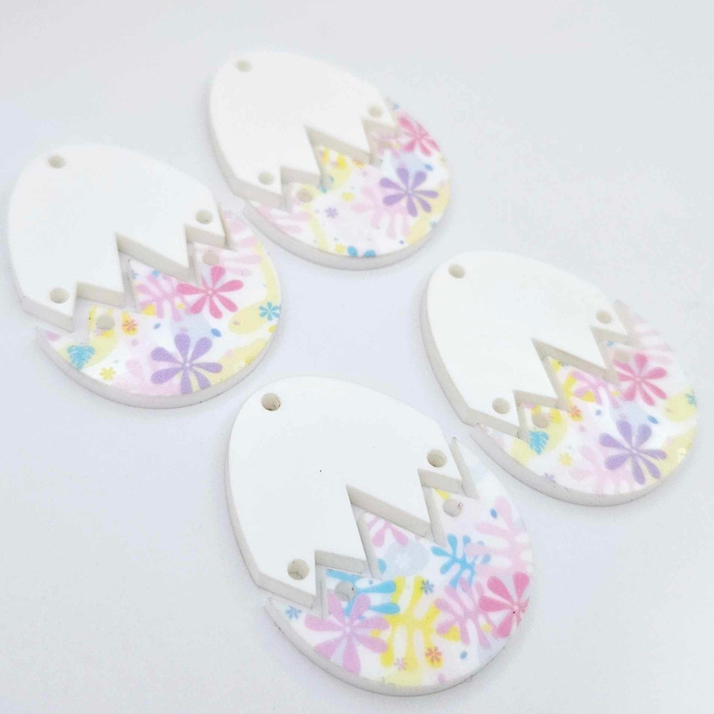 Four cracked egg earring blanks unassembled, white top halves and pastel pop UV printed bottom halves