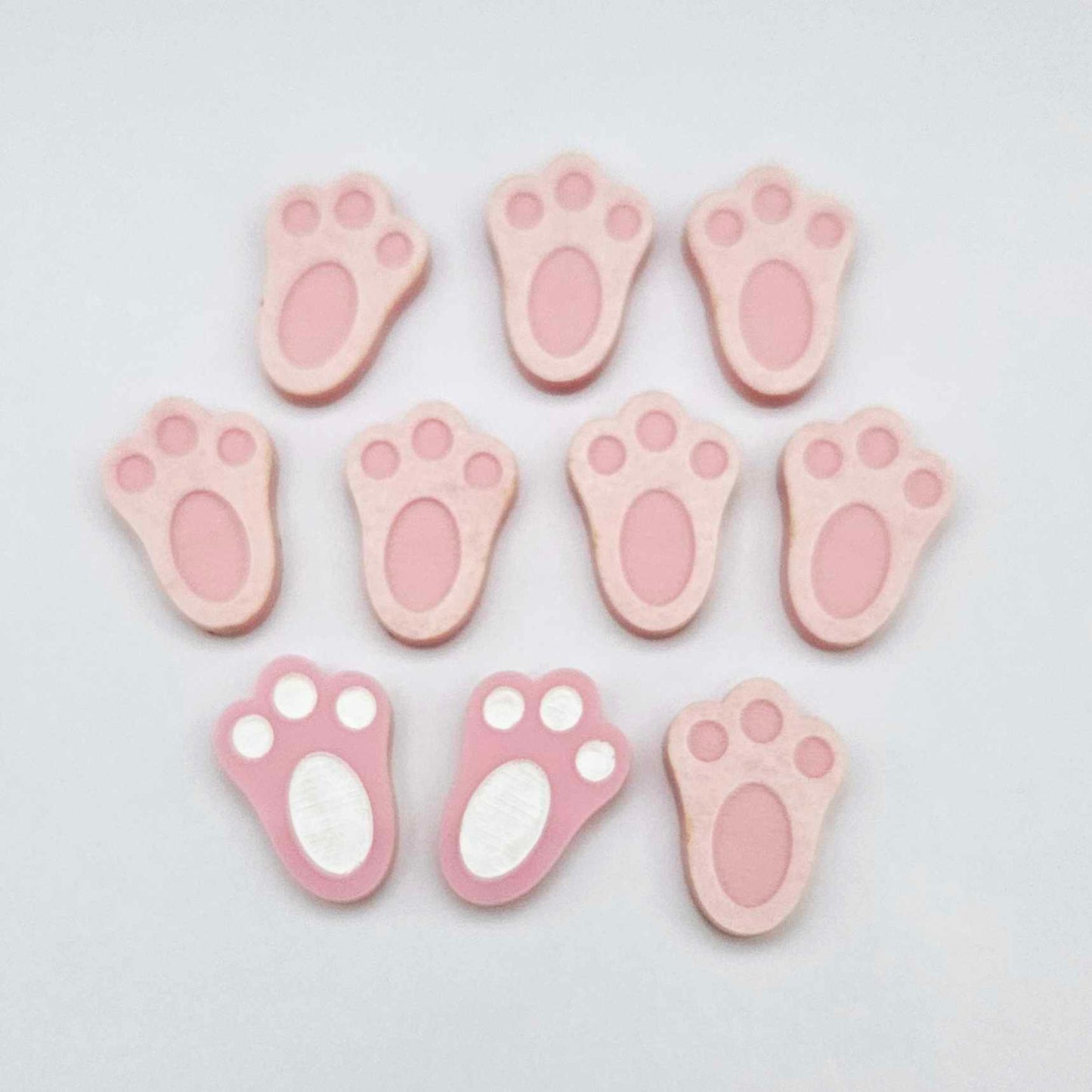 Pastel pink bunny paw print stud blanks showing two paint filled white and several unpainted pieces