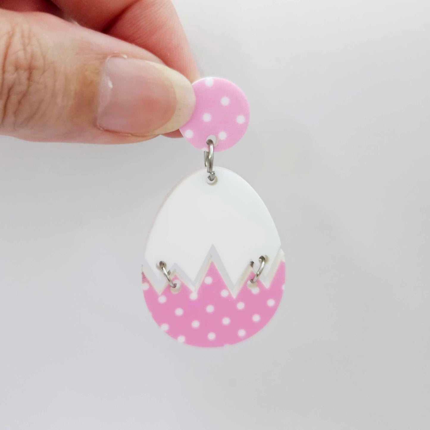 Assembled cracked egg dangle earring blank with white top and pastel pink polka dot UV printed bottom, hanging from a 14mm pink polka dot earring topper