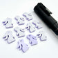 Pastel purple bunny stud blanks showing finished paint filled black eyelashes on two studs, with the rest shown as supplied with protective film