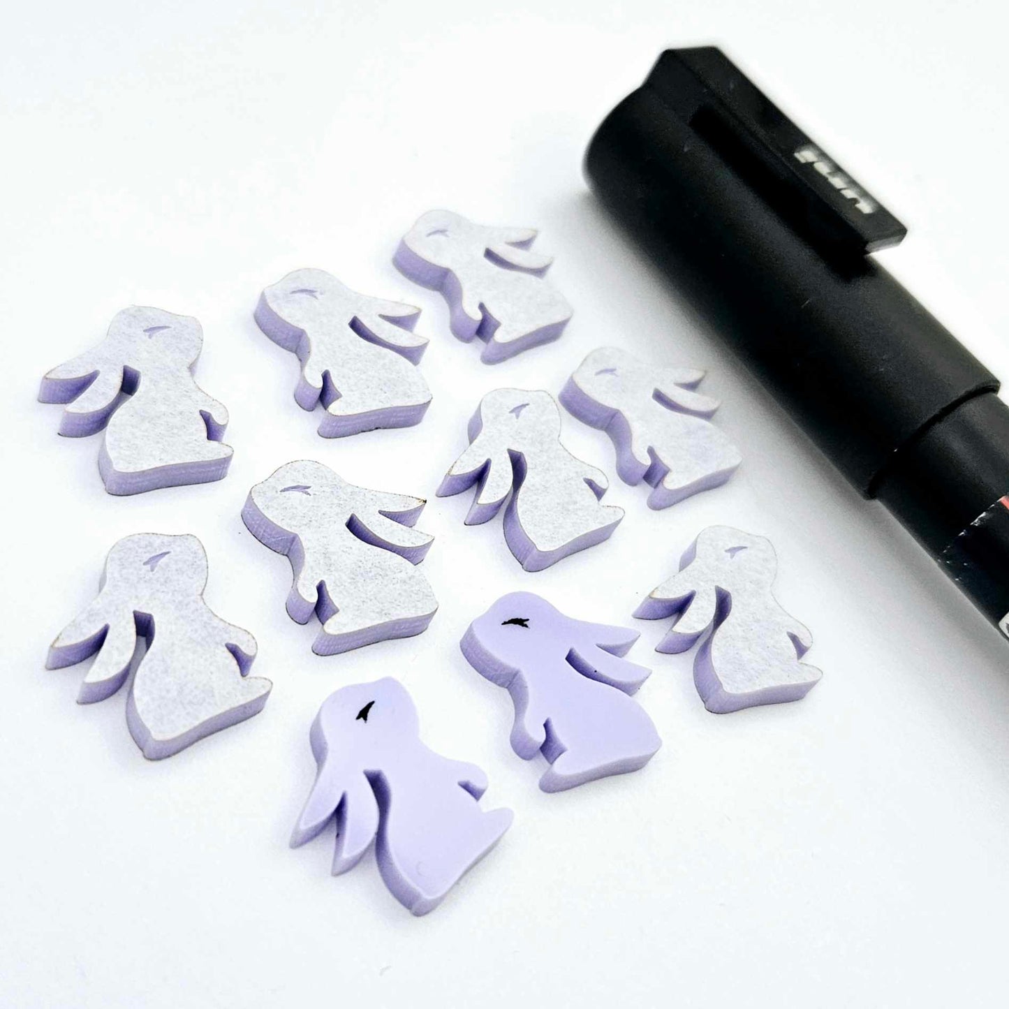 Pastel purple bunny stud blanks showing finished paint filled black eyelashes on two studs, with the rest shown as supplied with protective film