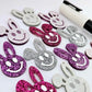38mm silver, hot pink and purple glitter acrylic bunny dangle blanks with engraved smiley face, some paint filled white and others unfilled with protective film on, shown with a White Posca paint pen