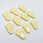 Pastel yellow bunny paw print stud blanks showing two paint filled white and several unpainted pieces