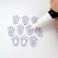 Pastel purple bunny paw print stud blanks showing two paint filled white and several unpainted pieces, with a white Posca paint pen included in the image