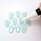 Pastel aqua bunny paw print stud blanks showing two paint filled white and several unpainted pieces, with a white Posca paint pen included in the image