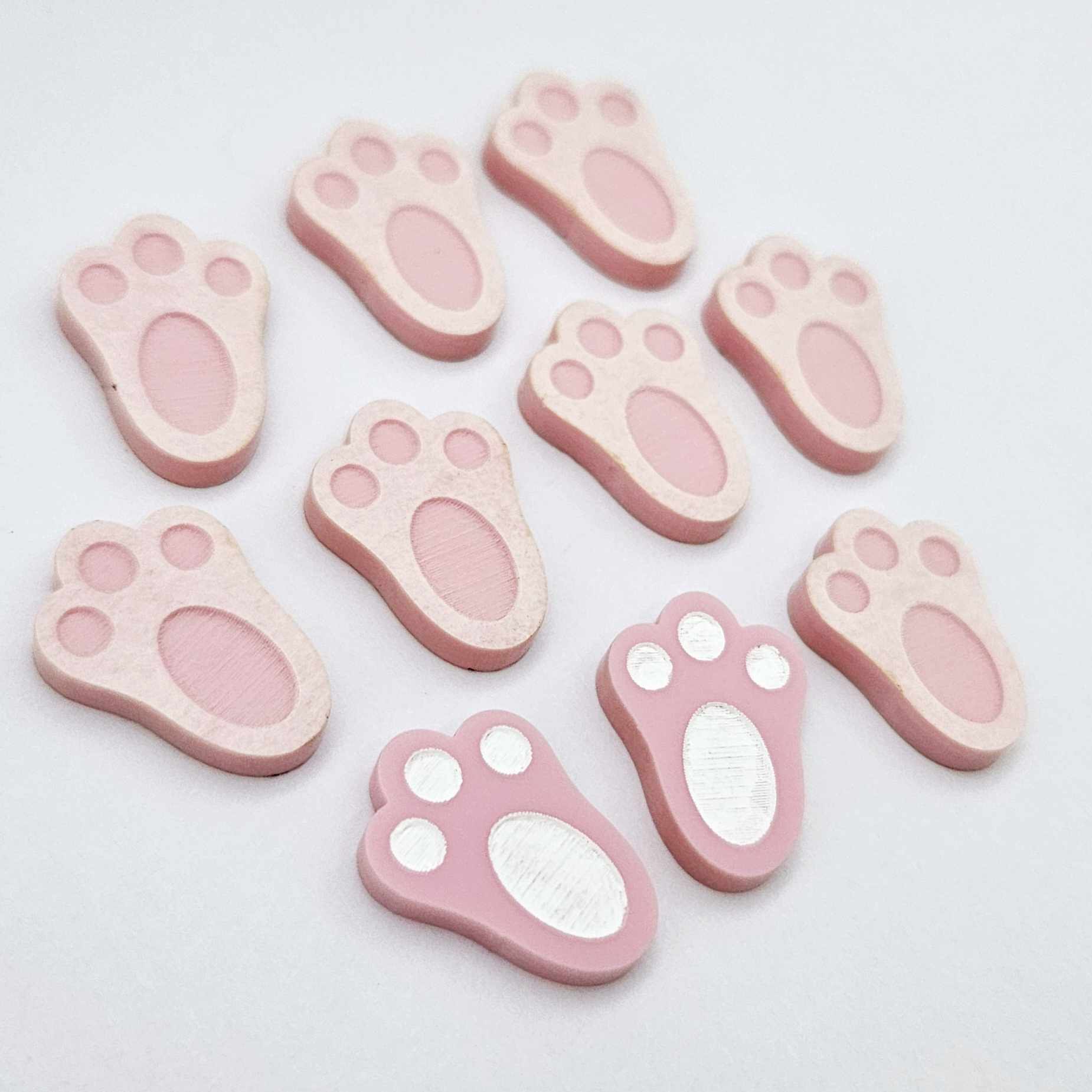 Pastel pink bunny paw print stud blanks showing two paint filled white and several unpainted pieces