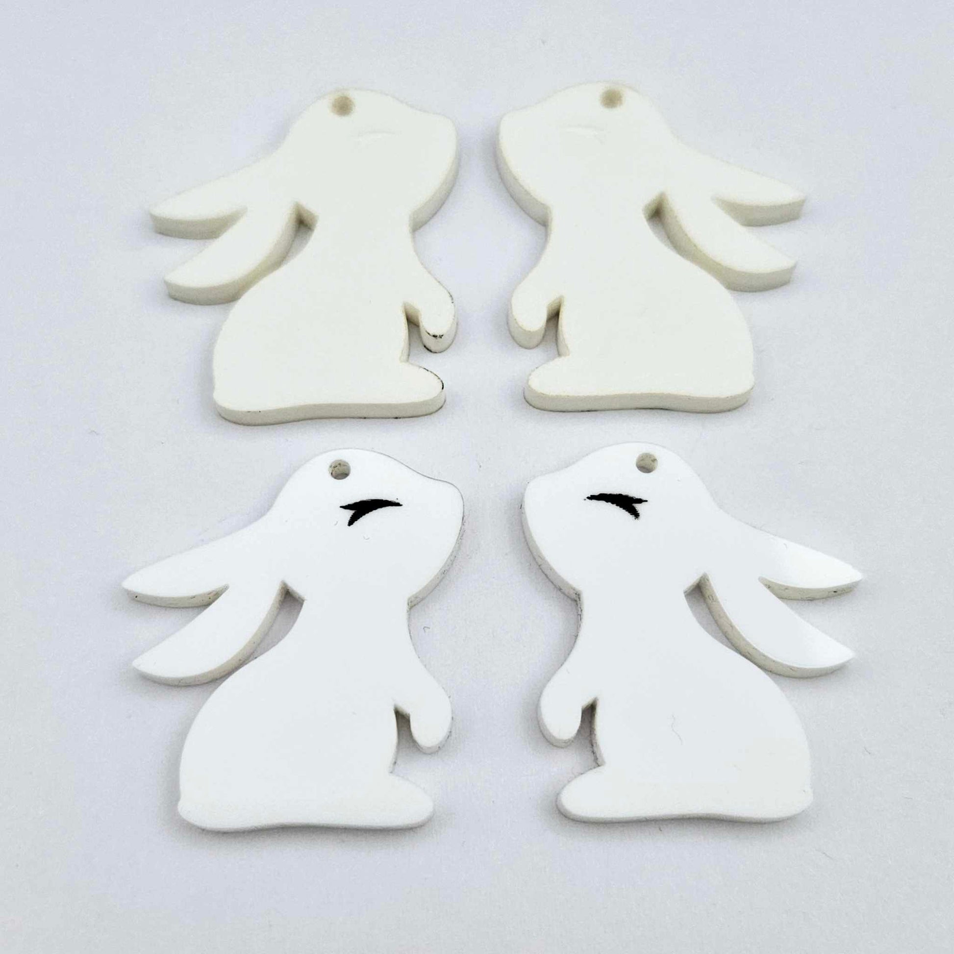 32mm white bunny dangle blanks showing paint filled black eyelashes on two pieces, with remaining pieces shown with protective paper as supplied