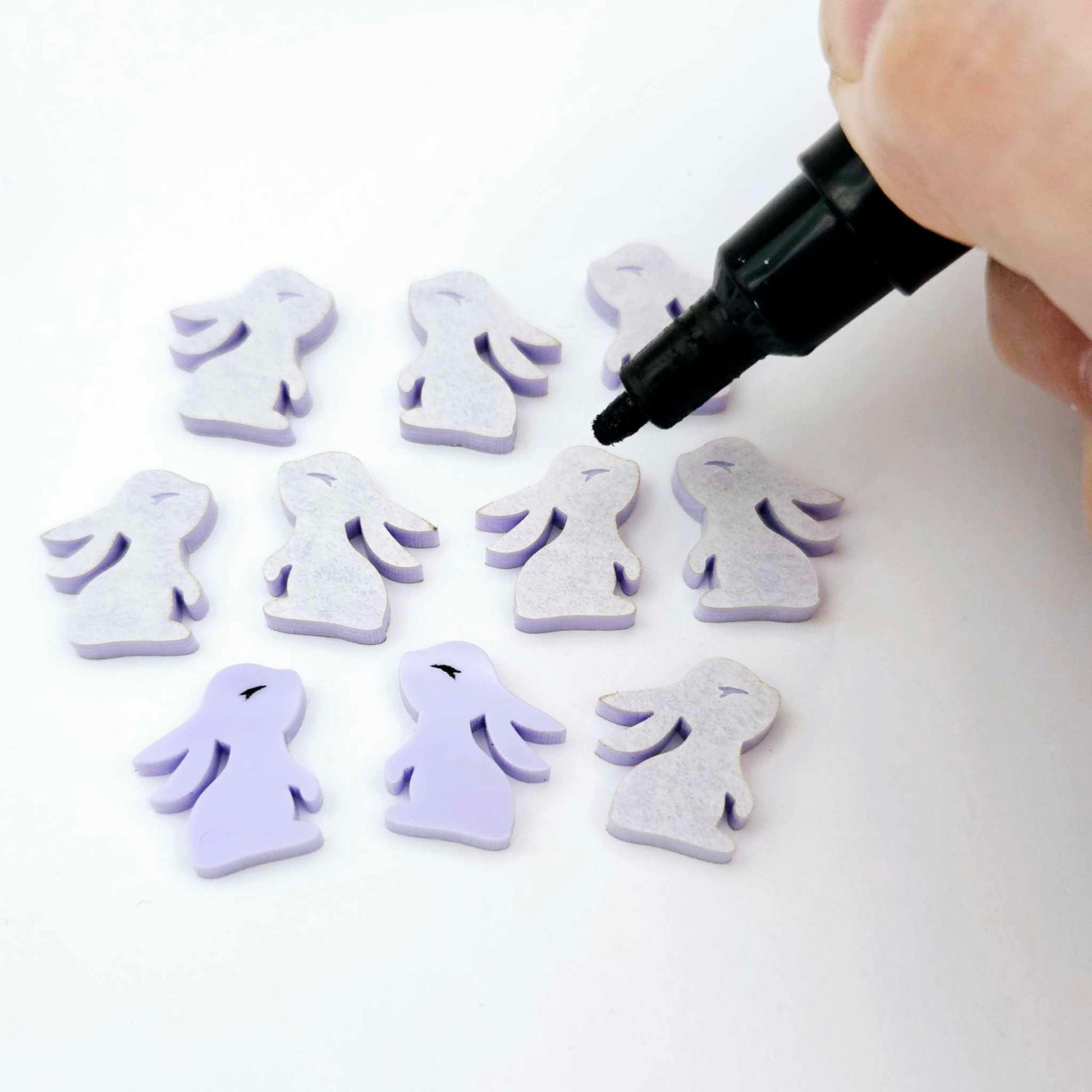 Pastel purple bunny stud blanks showing finished paint filled black eyelashes on two studs, with the rest shown as supplied with protective film