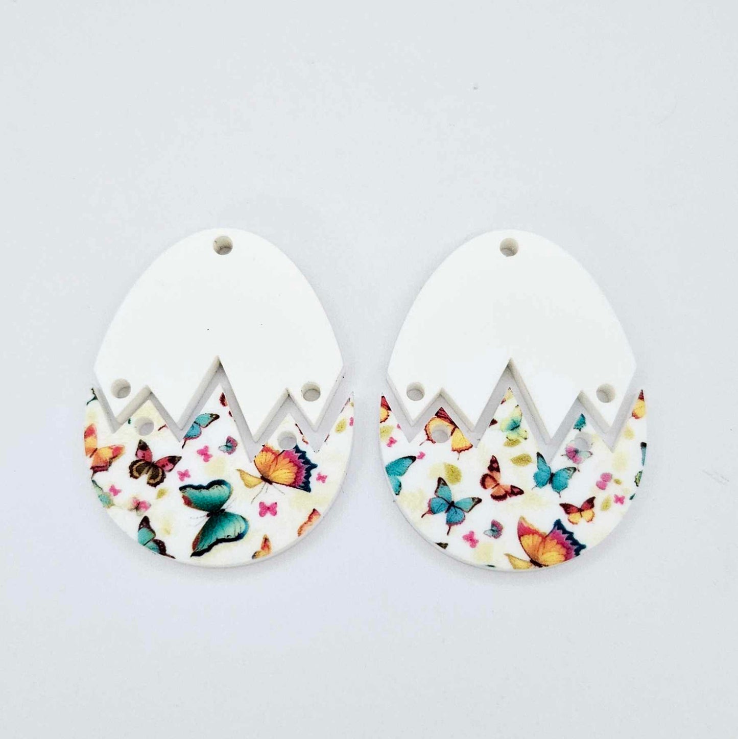 two cracked egg acrylic Easter earring blanks unassembled, white top halves and butterfly UV printed bottom halves