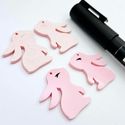 32mm Pastel pink bunny dangle blanks showing paint filled black eyelashes on two pieces, with remaining pieces shown with protective paper as supplied