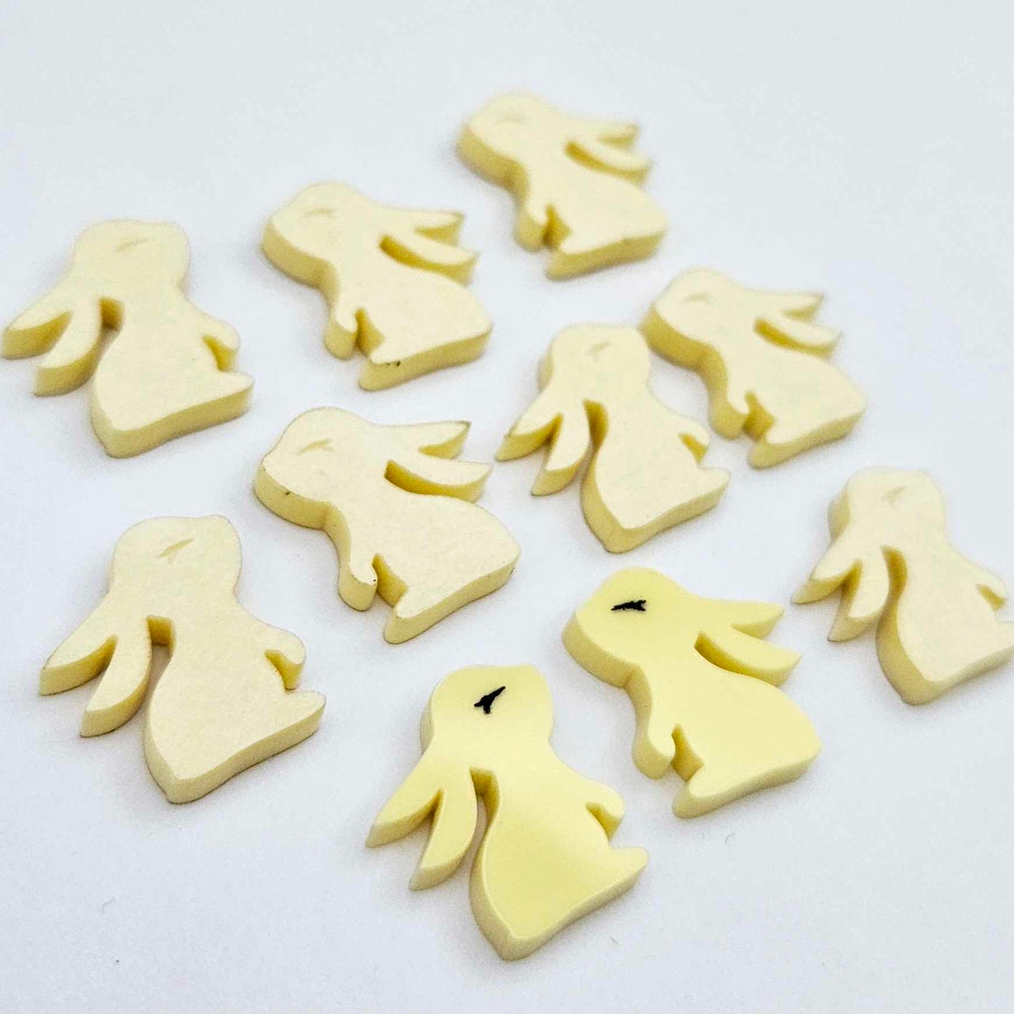 Pastel yellow bunny stud blanks showing finished paint filled black eyelashes on two studs, with the rest shown as supplied with protective film