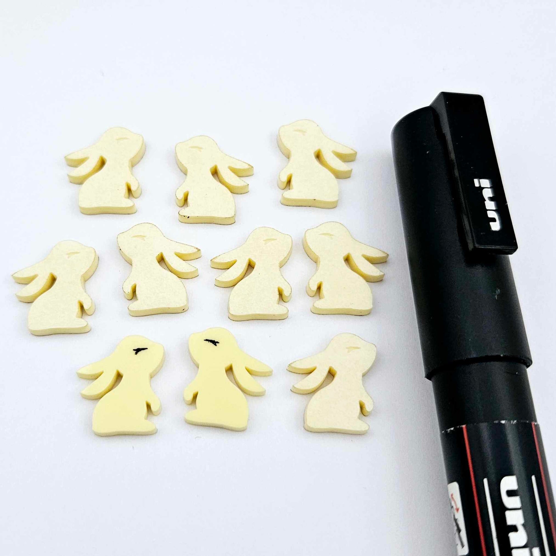 Pastel yellow bunny stud blanks showing finished paint filled black eyelashes on two studs, with the rest shown as supplied with protective film