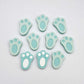 Pastel aqua bunny paw print stud blanks showing two paint filled white and several unpainted pieces