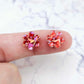 Two 10mm glitter flower stud blanks in Chunky Love colour, shown on a finger for size reference
