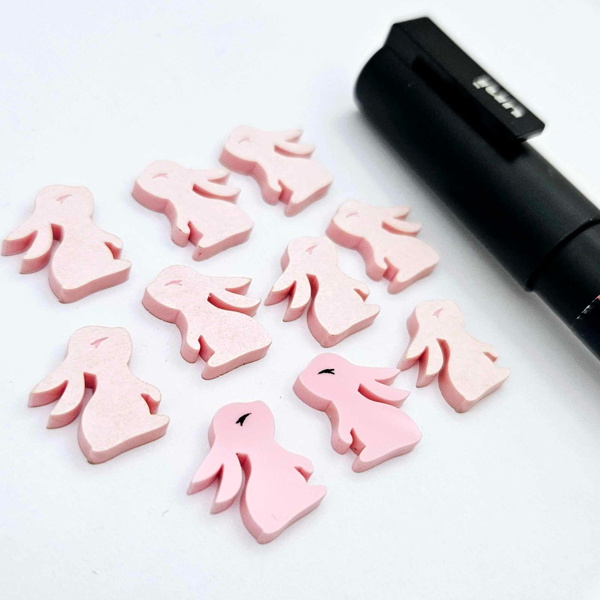 Pastel pink bunny stud blanks showing finished paint filled black eyelashes on two studs, with the rest shown as supplied with protective film